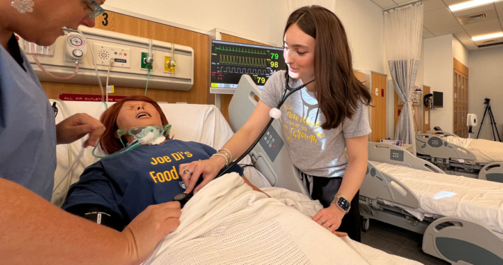 Hanna Johnson works on a patient in the simulation lab alongside Assistant Professor of Nursing, Julie Briere, MSN.