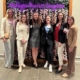 Photo of six women dressed professionally, looking at the camera smiling in front of a background that says, "Washington-Marriott Georgetown."
